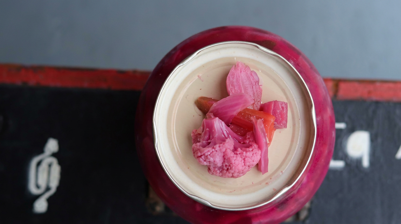 A jar of Blvb-blub KG kimchi topped with bright pink fermented vegetables.